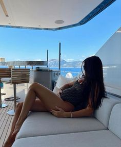 a woman sitting on top of a white couch next to a wooden table and water