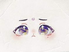 a close up of an embroidered face on a white shirt with blue eyes and eyelashes