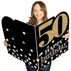 a woman holding up a black and gold 50th birthday sign