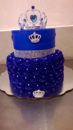 a three tiered blue cake with a crown on top