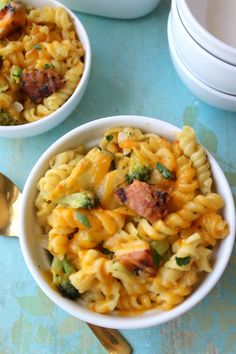 two bowls filled with macaroni and broccoli on top of a blue table