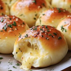 some bread rolls with cheese and herbs on them sitting on a white plate, ready to be eaten