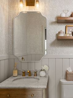 a bathroom with a sink, mirror and shelves on the wall next to the toilet