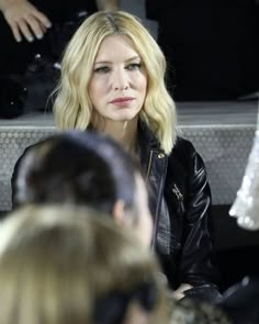 a woman with blonde hair sitting next to another woman in a black jacket and sunglasses