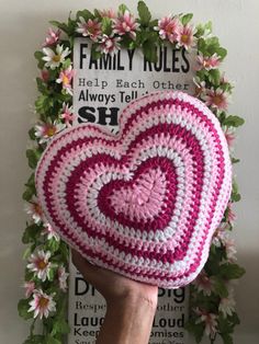 a crocheted heart is held up in front of a floral frame with the words family rules on it