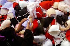 a pile of different colored stuffed animals on top of each other with hands reaching for them