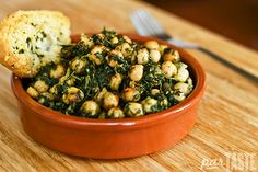 a bowl filled with spinach and bread on top of a wooden table