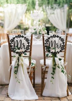 two chairs decorated with ribbons and bows are sitting in front of the table