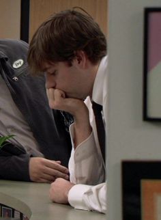 a man sitting at a desk with his hand on his chin