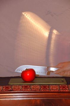 a red apple sitting on top of a table next to a knife