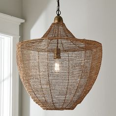 a woven light fixture hanging from a ceiling in a room with white walls and windows