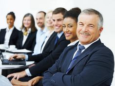 a group of business people sitting at a table with their laptops in front of them