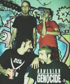 three men standing next to each other with graffiti on the wall behind them