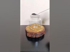 a glass jar sitting on top of a black table next to a wooden slice with a metal lid