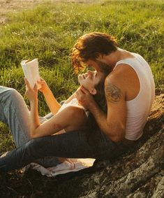 a man and woman are sitting on the grass reading books while looking at each other