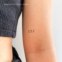 a woman's arm with the numbers 22 and 22 tattooed on her left arm