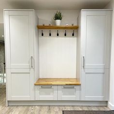 an empty room with white cabinets and wooden shelves on the wall, along with a potted plant