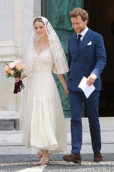 a bride and groom are standing in front of a building holding hands with each other