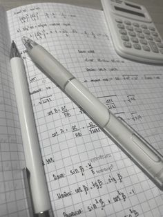 a pen and calculator sitting on top of an open notebook with some calculations