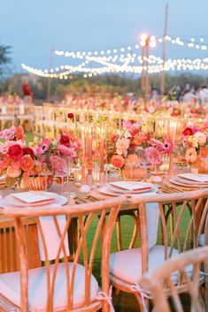 a table set up with flowers and candles for an outdoor wedding reception in the evening