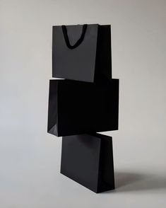 a black shopping bag sitting on top of a white floor next to a gray wall