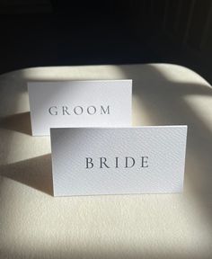 two white cards with the word groom and bride on them sitting on top of a bed