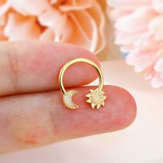 a hand holding a gold ring with a sun and moon on it