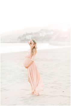 a pregnant woman wearing a flower crown on the beach