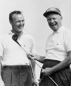 two men are laughing while holding golf clubs