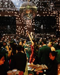 a woman in a red dress reaching up to catch a disco ball