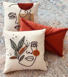 three decorative pillows with embroidered faces on them