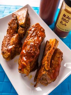 ribs covered in bbq sauce on a white plate next to a jar of bbq sauce