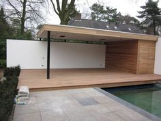 a house with a pool in front of it and a wooden deck next to it