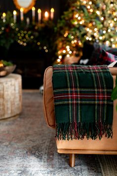 a living room decorated for christmas with lights on the trees in the background and plaid blanket