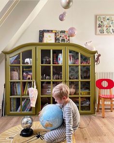 a little boy sitting on the floor with a globe