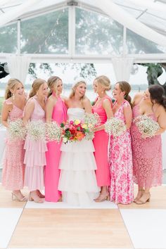 a group of women standing next to each other in front of a white and pink tent