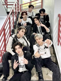 group of young men sitting on stairs giving the thumbs up sign in front of them