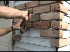 a man is using a hammer to fix a brick wall in front of a garage door