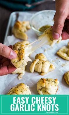 someone is dipping cheese into garlic knots on a sheet of parchment paper with the words easy cheesy garlic knots