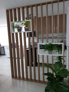 a room divider made out of wooden slats with plants in the middle and on top