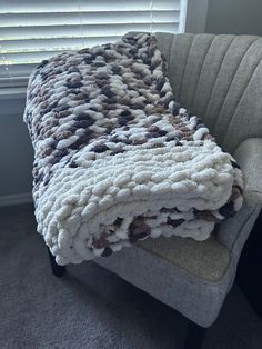 a blanket is sitting on top of a chair in front of a window with blinds