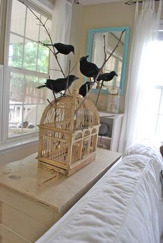 three black birds sitting on top of a birdcage in front of a window