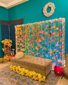 a room decorated with flowers and decorations on the wall, including a couch in front of a colorful backdrop