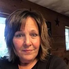 a woman in black shirt standing next to a window