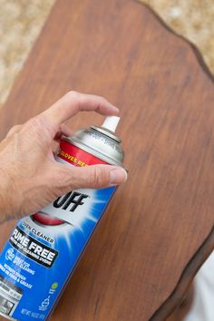 a person holding a spray can on top of a wooden table