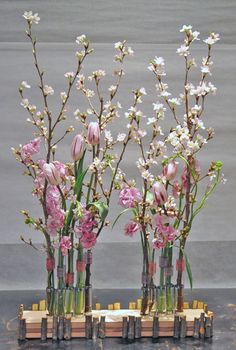 three vases with flowers in them sitting on a table next to each other,