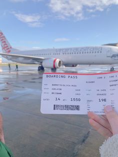 a person holding up a boarding pass in front of an airplane