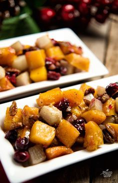 two white plates filled with food on top of a wooden table next to cranberries