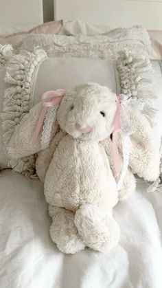 a white stuffed animal sitting on top of a bed