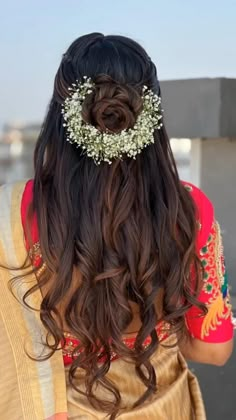 the back of a woman's head with long hair and flowers in her hair